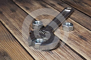 Wrench and screw nut on a wooden background