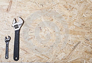 Wrench, small and big one on plywood background. Construction industry concept