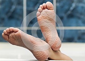 Wrinkled bare feet coming out from a bathtub. Young person getting a bath feet close-up indoor in bathroom interrior photo photo