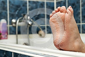 Wrinkled bare feet coming out from a bathtub. Young person getting a bath feet close-up indoor in bathroom interrior photo photo