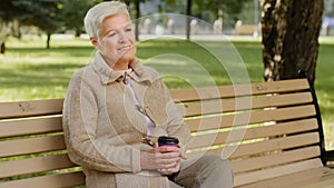 Wrinkled face of 60s happy elderly woman outdoors in park looking aside having wide smile, dental implants and