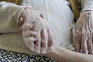 Wrinkled hand holding a younger hand