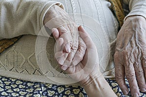 Wrinkled hand holding a younger hand