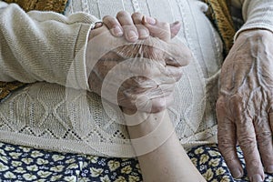 Wrinkled hand holding a younger hand