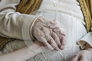 Wrinkled hand holding a younger hand