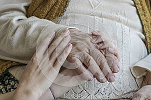 Wrinkled hand holding a younger hands