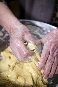 Wrinkled hands elderly hostess knead the pastry