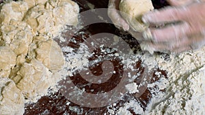Wrinkled hands of an elderly man knead the dough and make balls of kolobok.