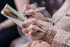 wrinkled hands for elderly person writing notes on here note book in living room