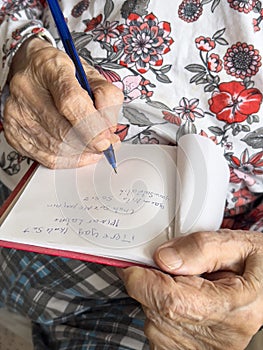 wrinkled hands of old woman writing shopping list in turkish