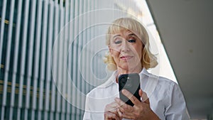 Wrinkled lady scrolling smartphone walking street closeup. Mature woman browsing