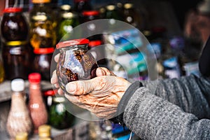 Wrinkled old female hands hold jar with jam