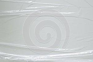 Wrinkled plastic wrap on white color background. Crumpled transparent plastic cellophane. Reflecting light and shadow on