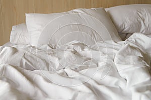 Wrinkled white blanket with soft pillows on comfortable bed in the morning. messed up after nights sleep