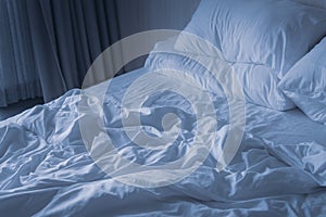 Wrinkled white blanket with soft pillows on comfortable bed in the morning. messed up after nights sleep