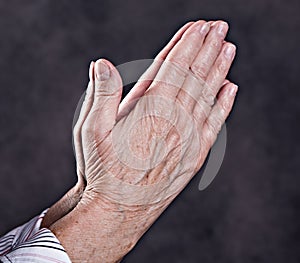 Wrinkly hands of elderly woman praying