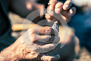 Wrinkly hands putting a small fish on a fishing rod