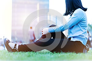 Wrist hand pain women sit on the green grass in the playground on sunset, city lifestyle concept