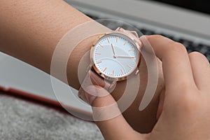 Wrist watch on girl`s hand in front of a notebook computer