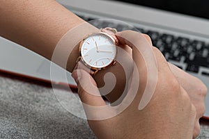 Wrist watch on girl`s hand in front of a notebook computer