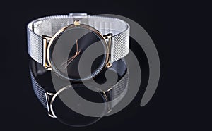 Wrist watch with metal strap for women on black background