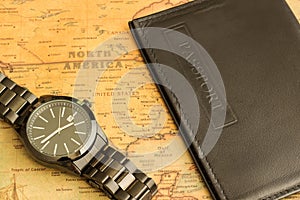 Wrist watch and passport on the table with a map of North America