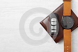 Wristwatch, remote car key and wallet on light background, top view