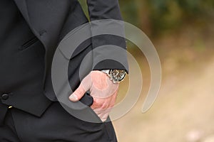 Wristwatches on hands close-up, dressing, man`s style, stylish man. Elegant young handsome man. Men`s jacket, hand cover the