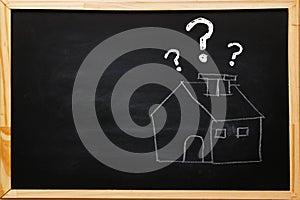 Write house symbol with question marks on blackboard with chalk