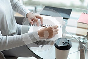 Write daily list before start each day. hands of businesswoman writing in her notebook while working at desk