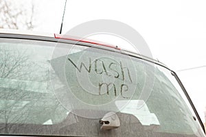 Write the words wash me on the very dirty surface of the car. Concept car wash