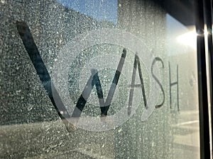 Write the words wash on the very dirty surface glass window. Concept wash.