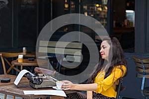 Writer female working in a coffee shop using a retro typewriter
