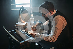 Writer in glasses writes novel with a feather