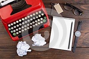 Writer or journalist workplace - vintage red typewriter, glasess and notepad on the wooden desk