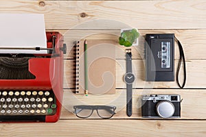 Writer or journalist workplace vintage red typewriter, photo camera, cassette recorder on the wooden desk