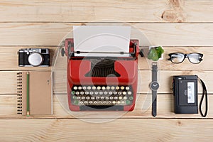 Writer or journalist workplace vintage red typewriter, photo camera, cassette recorder on the wooden desk