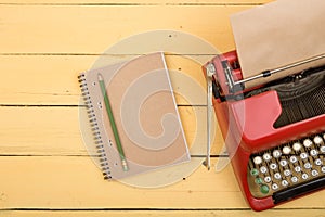 Writer or journalist workplace - vintage red typewriter on the yellow wooden desk