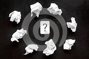 Writer`s block concept. Question mark among crumpled paper on black background top-down