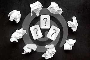 Writer`s block concept. Question mark among crumpled paper on black background top-down