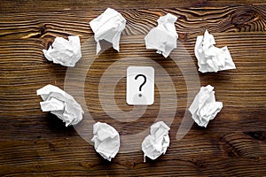 Writer`s block concept. Question mark among crumpled paper on dark wooden background top-down