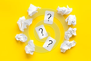 Writer`s block concept. Question mark among crumpled paper on yellow background top-down