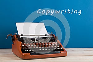 writer's workplace - typewriter on blue blackboard background with text "Copywriting photo