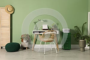 Writer`s workplace with typewriter on wooden desk near pale green wall in room