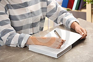 Writer signing autograph in book at table