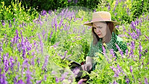 Writer woman working on laptop in field flowers. mobile Internet in rural areas