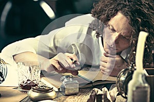 Writer at work. Handsome young writer sitting at the table and writing something in his sketchpad