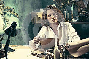 Writer at work. Handsome young writer sitting at the table and writing something in his sketchpad