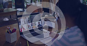Writing child in striped top wearing headset at wood table, using laptop, notebook, pen, copy space