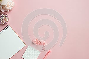 A writing concept with blank book, pen, pink flowers over the pink background.
